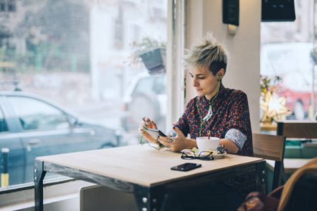 Young and lovely gender blend woman, enjoying a cup of coffee at the cafe.